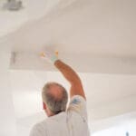 Professional painter applying paint to a ceiling during an interior painting project