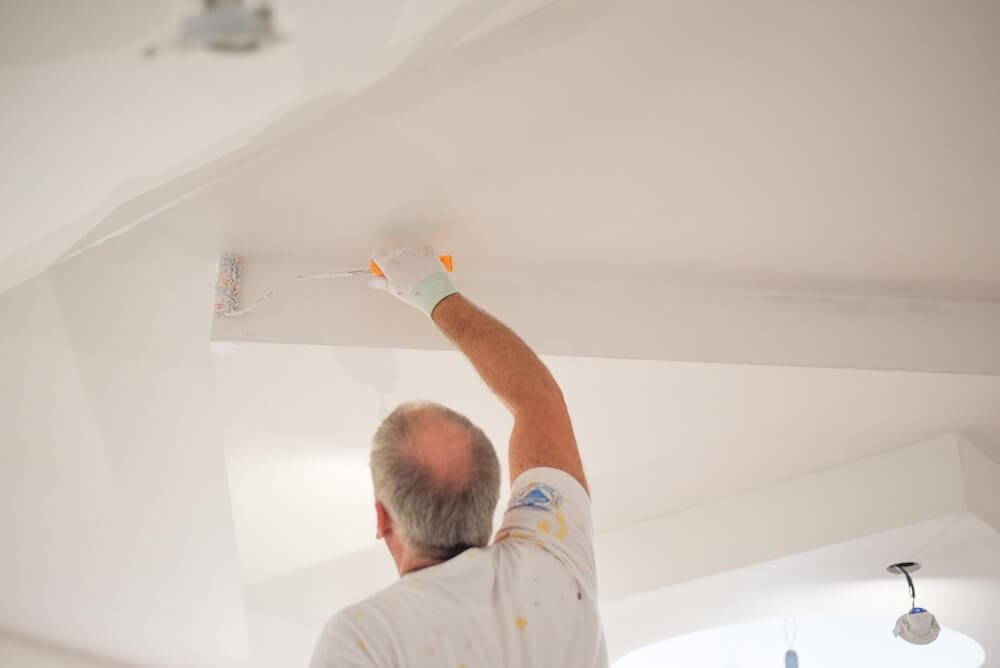 Professional painter applying paint to a ceiling during an interior painting project