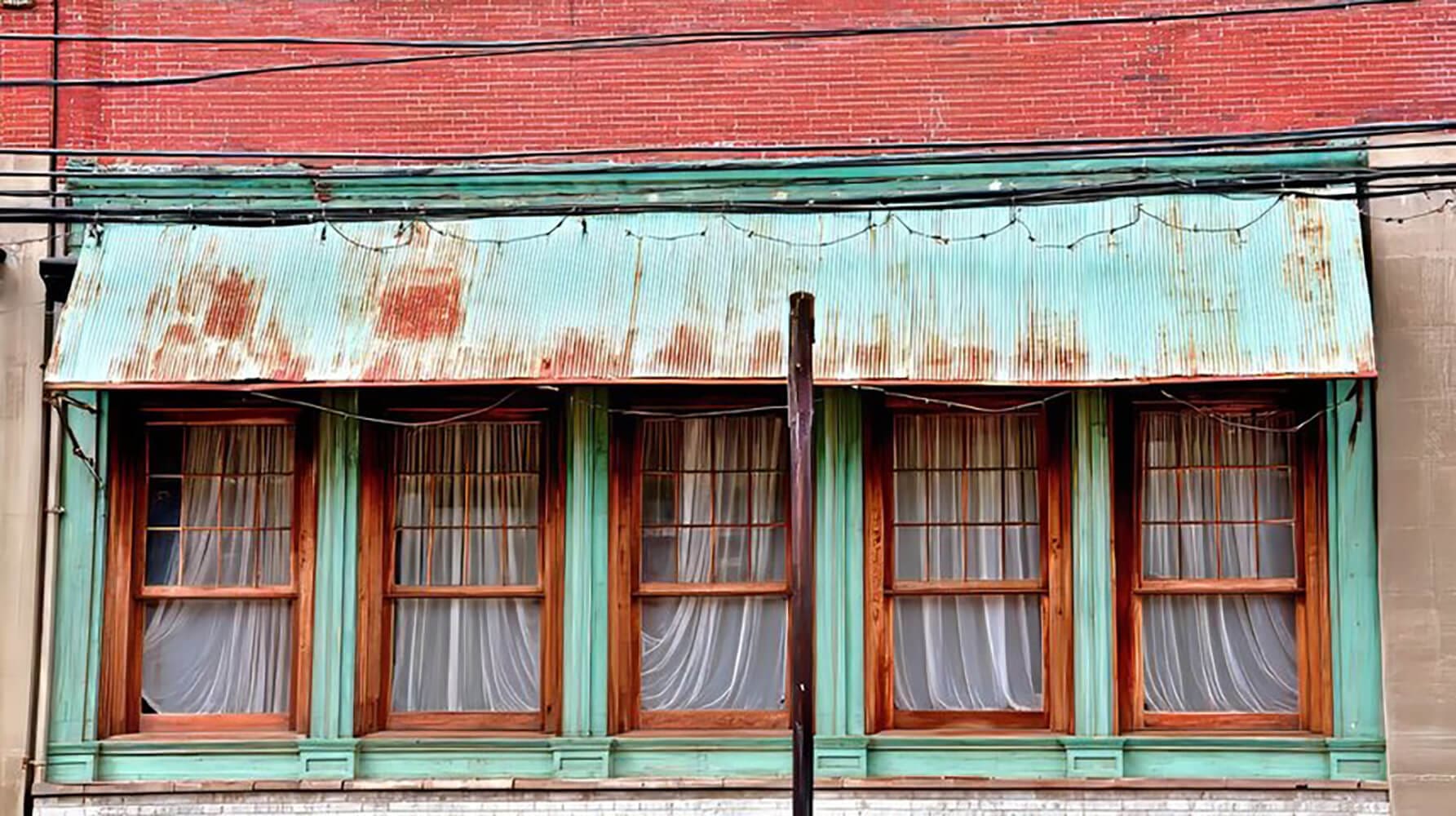 Weathered commercial storefront with faded and peeling paint showing signs that commercial painting in Baton Rouge is overdue.