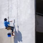 Professional painter applying paint to a commercial building exterior in Baton Rouge