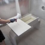 Professional spraying a smooth white finish on cabinet doors, demonstrating how cabinet painters get a flawless finish.