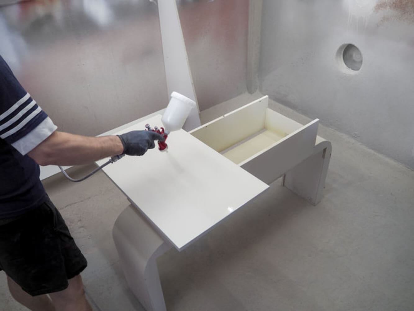 Professional spraying a smooth white finish on cabinet doors, demonstrating how cabinet painters get a flawless finish.