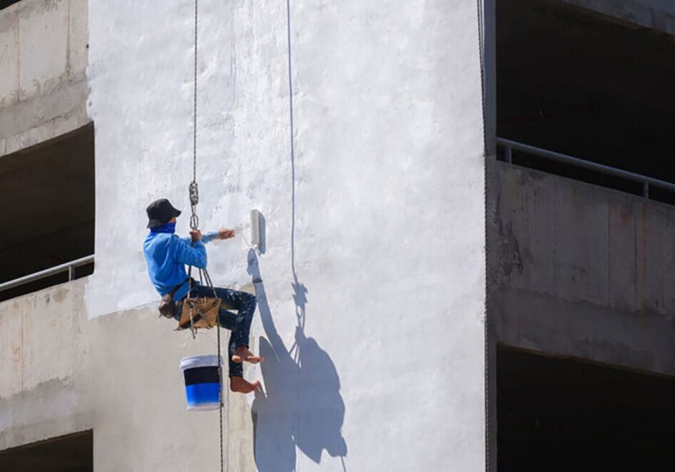 Professional painter applying paint to a commercial building exterior in Baton Rouge