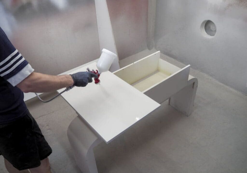 Professional spraying a smooth white finish on cabinet doors, demonstrating how cabinet painters get a flawless finish.